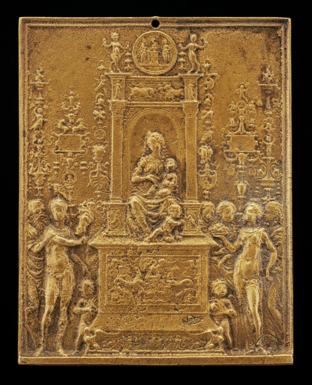Goldene Plakette mit einer detaillierten Skulptur einer Frau in einem langen Kleid und einem Mann in einem Anzug und Krawatte auf schwarzem Hintergrund, umrahmt von einem prunkvollen goldenen Rahmen.
