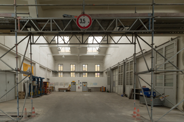 Lagerhalle mit ausführlichem Gerüst, Verkehrszeichen, Metallstangen, ein Schild, Maschinen, eine Tür, Fenster, Wände, Deckenleuchten und Dach.