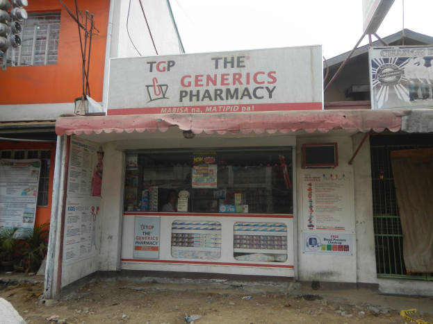 Übersicht der 'The Generics Pharmacy'-Filiale mit umliegenden stadtischen Elementen unter einem klaren blauen Himmel.