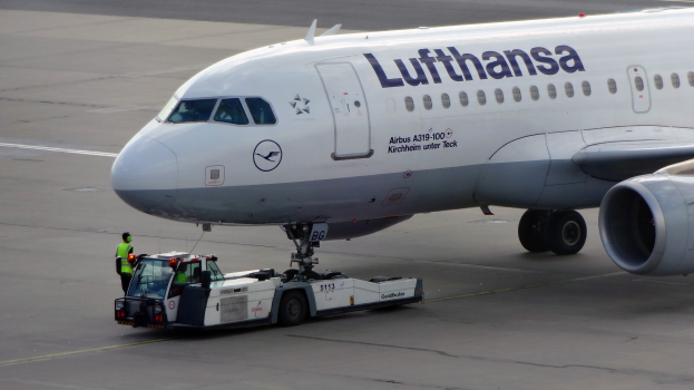 Ein Lufthansa Airbus A319-100-Flugzeug wird auf dem Rollfeld des Frankfurter Flughafens positioniert, mit einem Fahrzeug und einer Person in der Nähe, bereit zum Start.