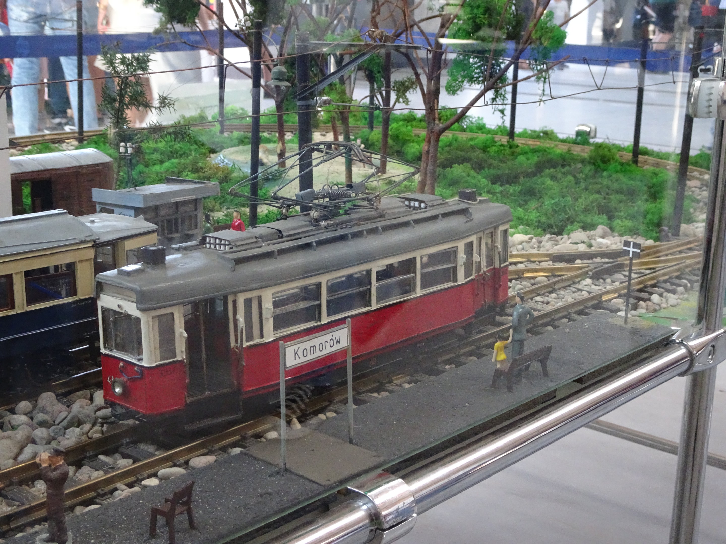 Ein Modellzug in einer Glasvitrine mit Miniatur-Eisenbahnlandschaft und Zuschauern