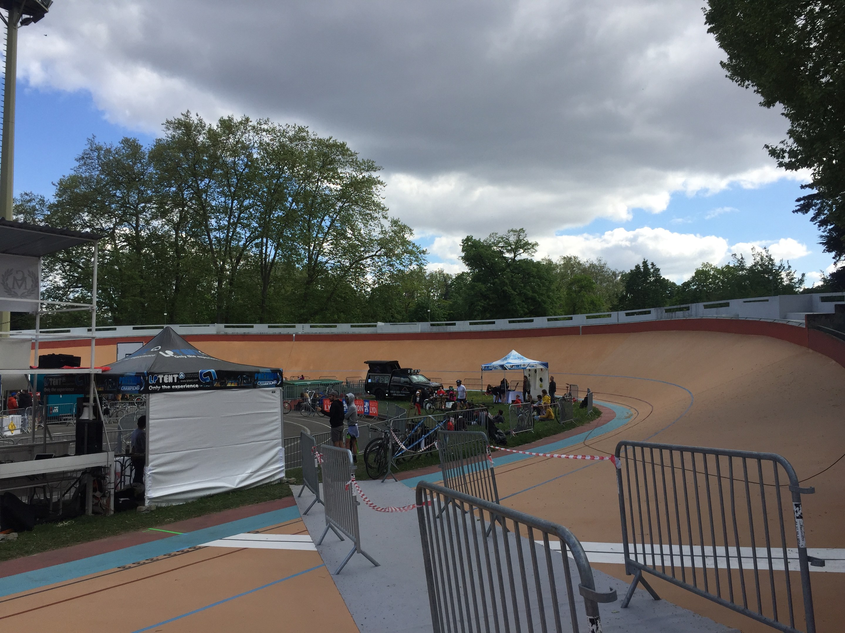 Eine Gruppe von Radfahrern auf einer Schmutzspur bei den UCI BMX-Weltmeisterschaften 2018, mit Zuschauern, Zelten und Fahrzeugen im Hintergrund.