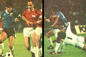 Eine Gruppe von Männern, die Fußball auf einem Feld spielen, mit einem, der den Ball tritt, und anderen, die versuchen, die Kontrolle zu übernehmen, und einer Tafel im Hintergrund, die eine Stadionatmosphäre suggeriert.