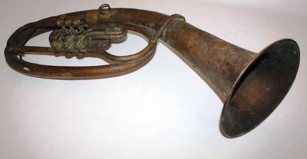 Altes Messinghorn mit glänzendem Finish, gebogenem Hals und aufgeblasenem Trichter, verziert mit kunstvollen Gravuren, auf einem weißen Hintergrund.