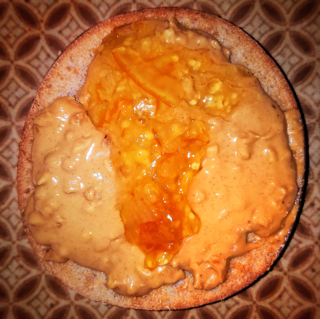 Ein leicht getoastetes Sandwich mit einer dicken Schicht Erdnussbutter auf einem Teller.