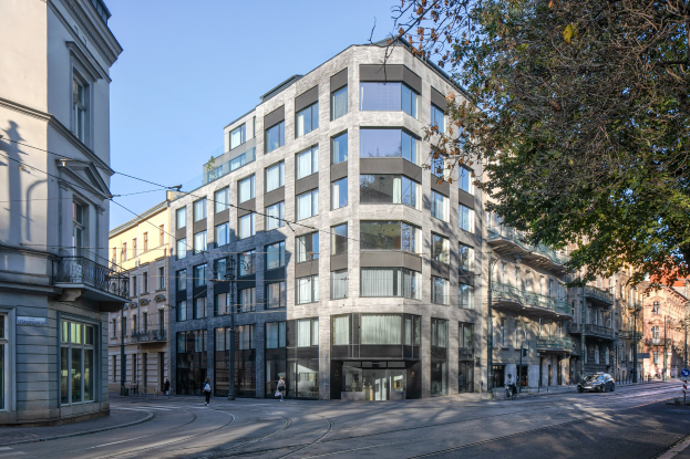 Großes Bürogebäude mit vielen Fenstern, umgeben von Straßeninfrastruktur, Fahrzeugen, Fußgängern, Bäumen und einem bewölkten Himmel, das als neuer Hauptsitz des Unternehmens dient.