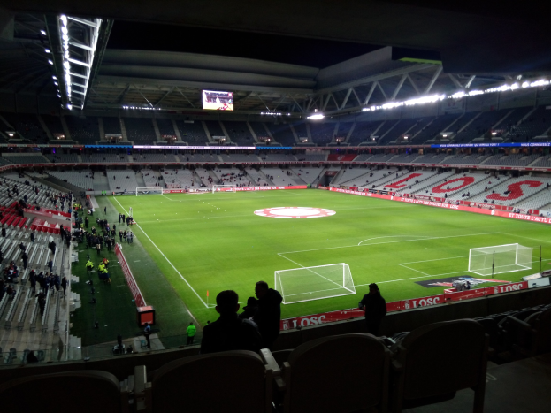Großes Stadion mit Zuschauern bei einem Fußballspiel im Estadio Santiago Bernabeu in Madrid, Spanien, mit sitzenden und stehenden Zuschauern unter Stadionbeleuchtung und einem großen Bildschirm.