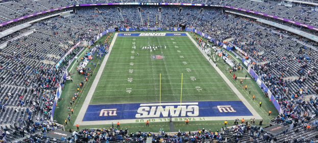 Ein Fußballstadion voller Zuschauer, Spieler, Pfosten und Schilder mit Text, mit Reihen von Stühlen, die eine lebendige Atmosphäre schaffen.