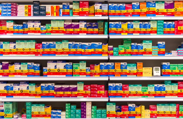 Ein Apothekenregal mit verschiedenen Medikamenten, darunter Schachteln und andere Gegenstände, die ordentlich auf den Regalen angeordnet sind.