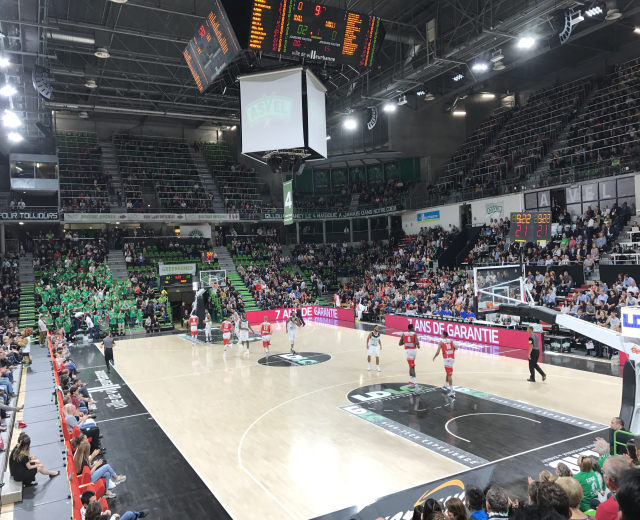 Basketballspiel zwischen Asvel und Galatasaray in einem vollen Hallenstadion mit Anzeigetafeln und Deckenbeleuchtung.