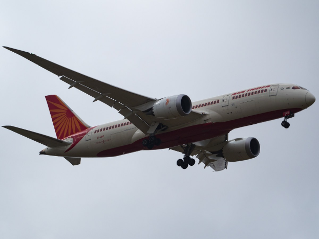 Air India-Flugzeug im Flug mit ausgefahrenem Fahrwerk, Tragflächen und Motoren sichtbar gegen den Himmel.