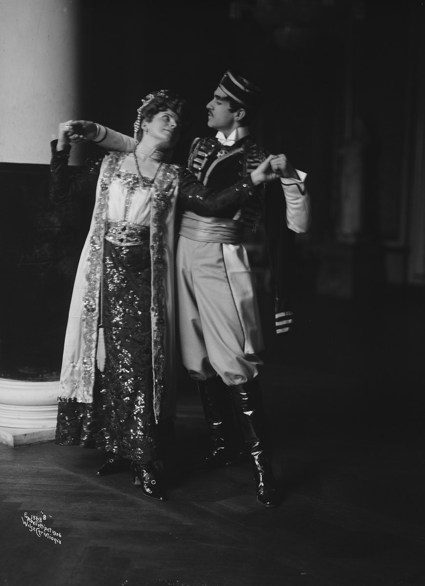 Schwarzes und weißes Foto eines Mannes und einer Frau, die in einem Ballsaal tanzen, mit einer Säule und einer Wand im Hintergrund; der Mann trägt Schuhe, was darauf hinweist, dass sie eine Vorstellung geben.