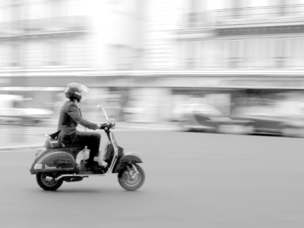 Eine Person, die ein Scooter auf einer Straße fährt.