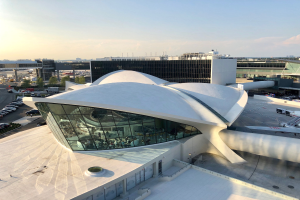 Luftaufnahme des neuen Terminalgebäudes am Los Angeles International Airport mit Fahrzeugen, Bäumen und umliegenden Gebäuden unter einem bewölkten Himmel.