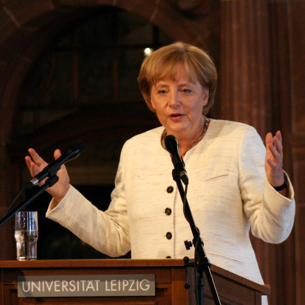 Bundeskanzlerin Angela Merkel bei einer Rede an einem Pult mit einem Mikrofon und einem Glas Wasser an der Universität Leipzig.